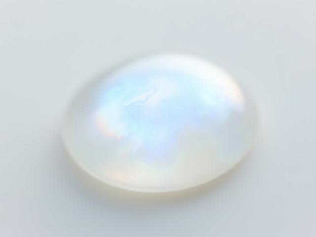 A luminous, iridescent white moonstone cabochon, glowing softly.