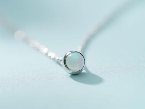 Macro shot of a tiny gemstone set securely in a sterling silver bezel on a pendant.