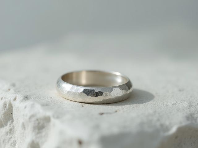 Dainty hammered silver stacking ring on a natural stone surface.