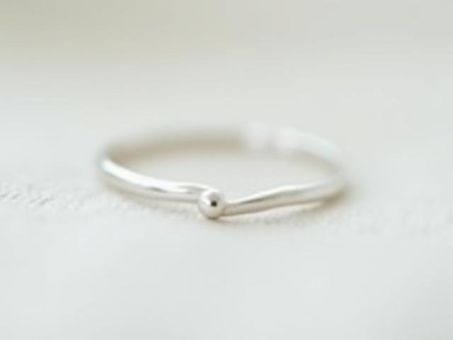 A delicate sterling silver ring featuring a tiny, subtle dot detail.